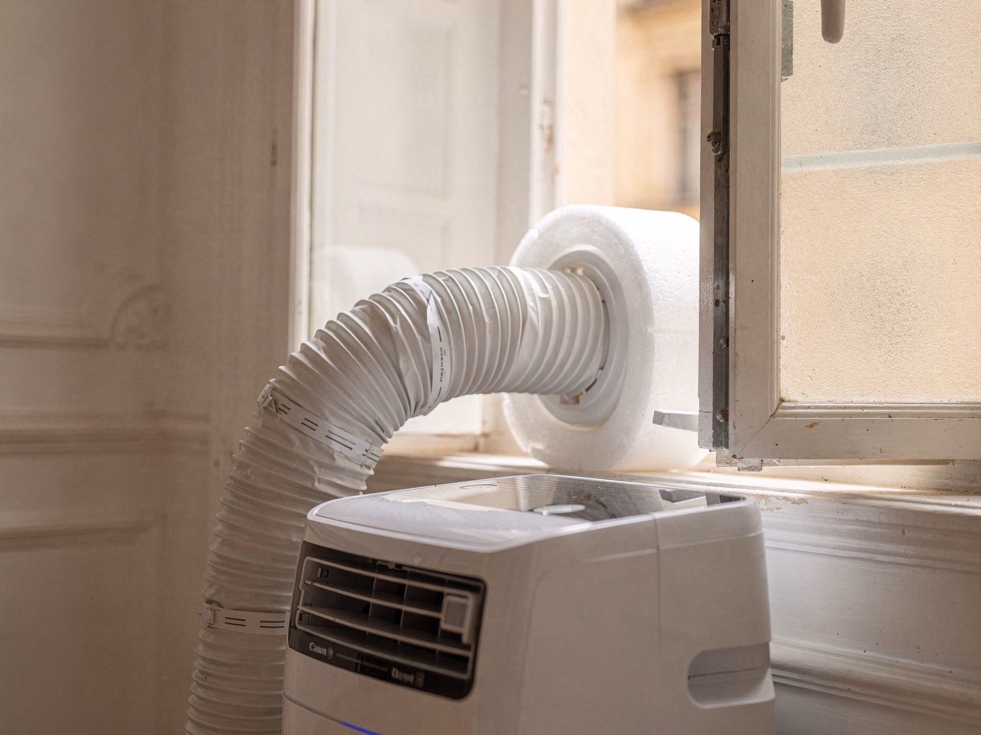 Détail d'un tuyau d'évacuation de climatiseur mobile installé proprement dans une fenêtre