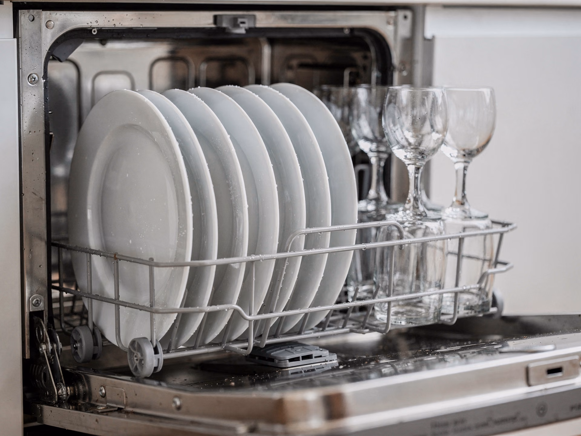 Panier intérieur d'un lave-vaisselle compact 6 couverts entièrement chargé avec assiettes et verres